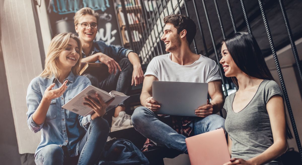 Stock picture showing a group of college students sitting and laughing. 